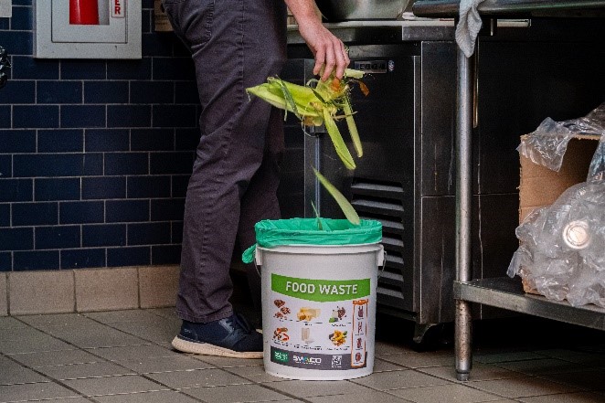 hand throwing away food scraps in compost bin