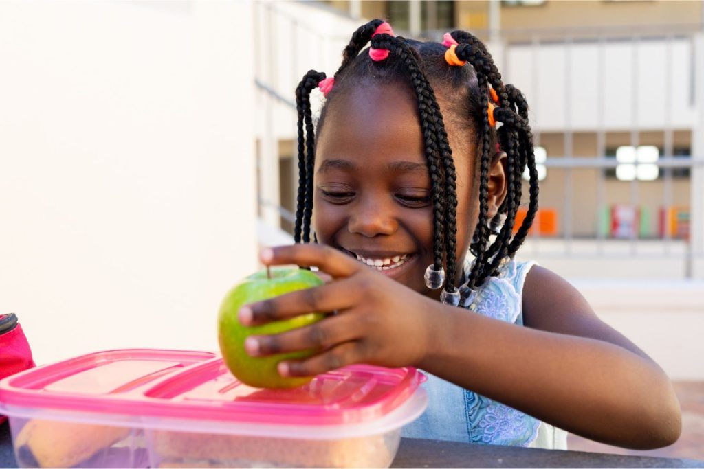 A girl with her school lunch in front of her.