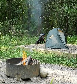 A campfire with a tent in the background.