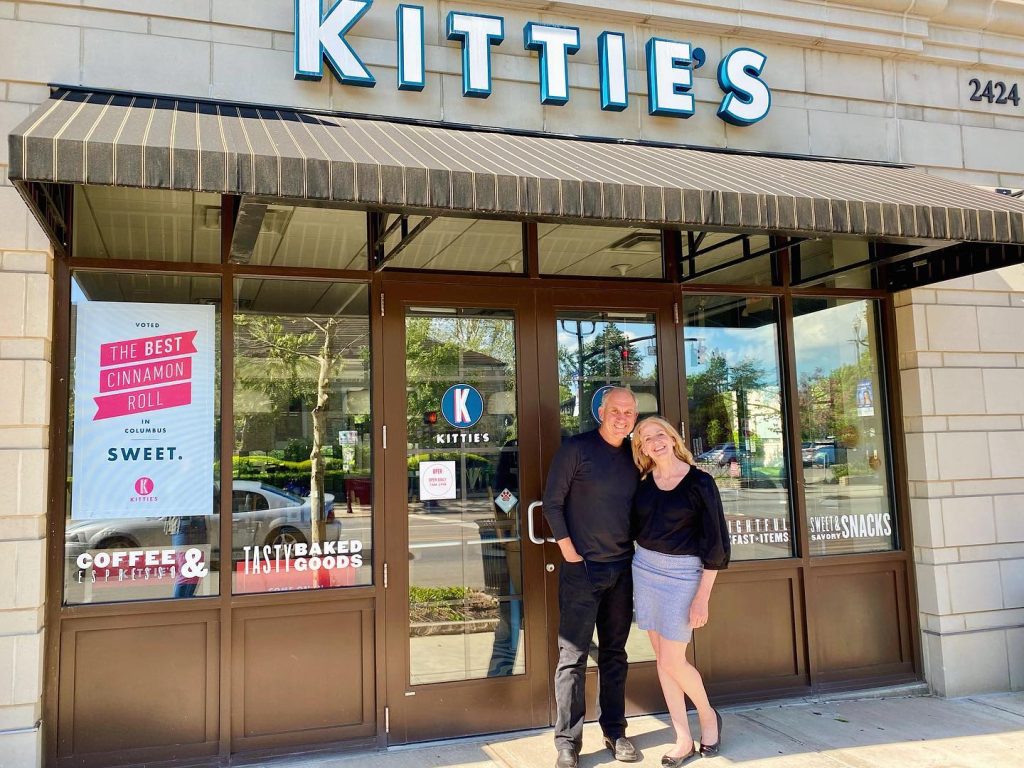 Two people standing in front of Kittie's Cakes.