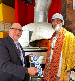 Two men standing in front of a pizza oven