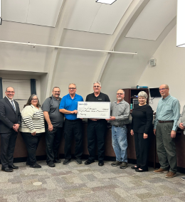 A group of people holding a large check