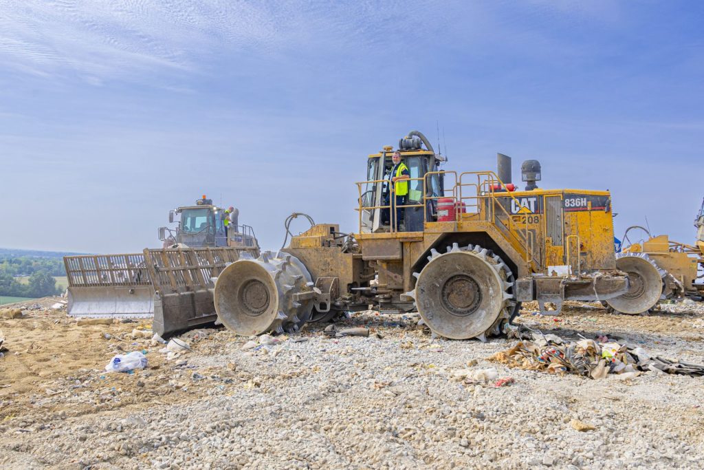 Two tractors pushing trash in the landfill