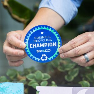 Business owner adding SWACO recycling champion sticker to their window