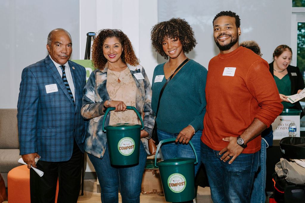 Four individuals smile for the camera during a waste reduction event