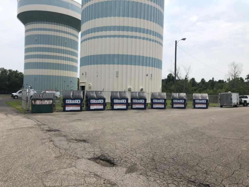 Dumpsters with water towers behind them.