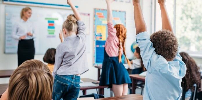 Kids raising hands in classroom